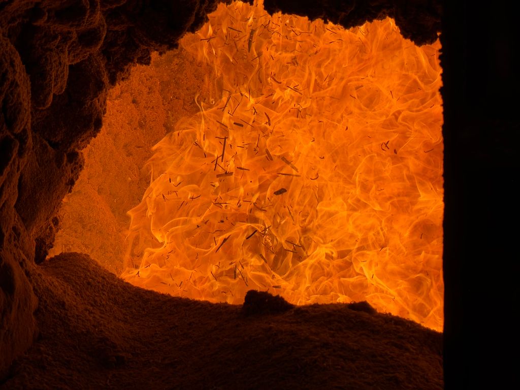 Captivating orange flames in an industrial furnace viewed from below, showcasing intense heat and texture.