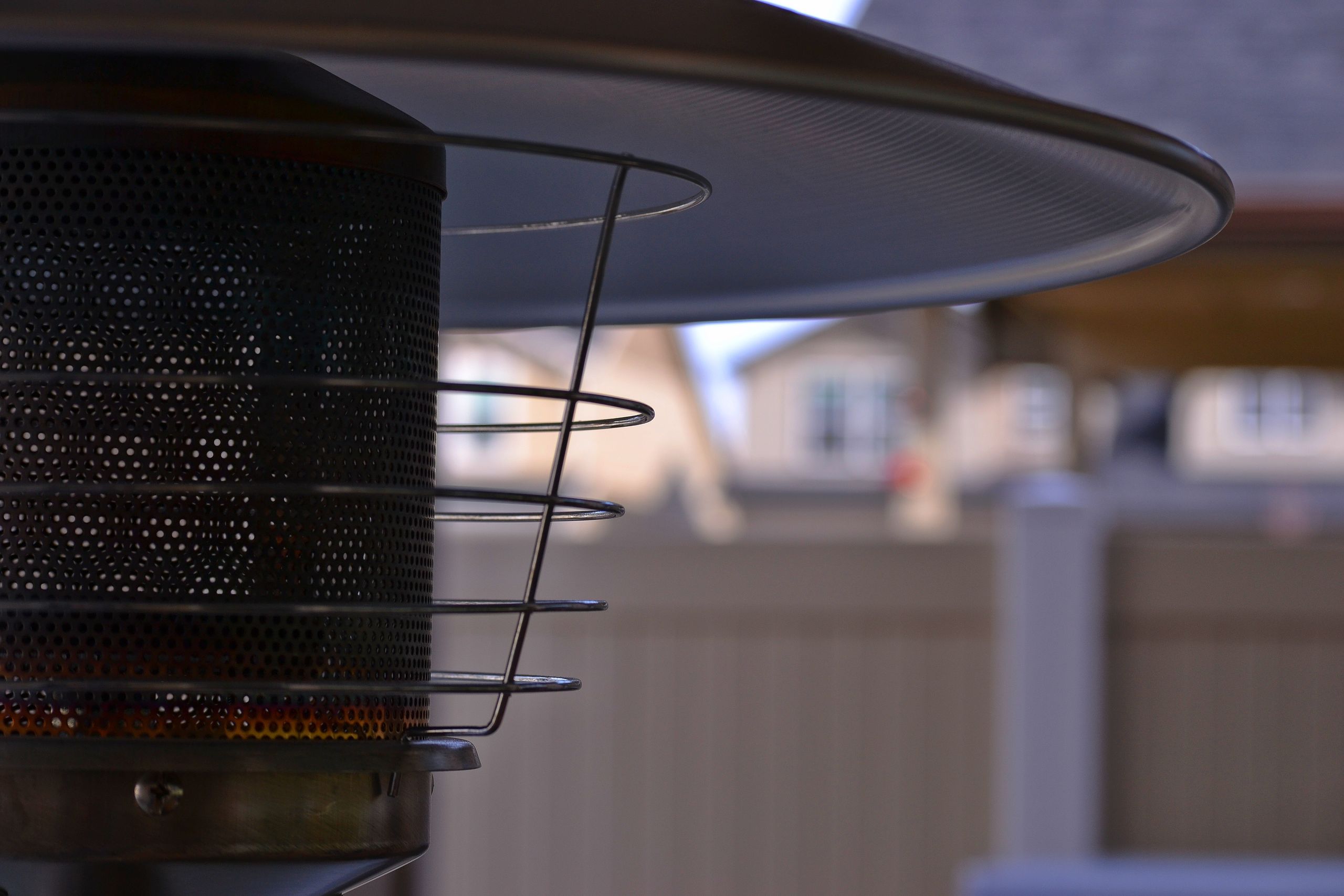 Detailed view of a modern outdoor patio heater with blurred suburban background, perfect for outdoor comfort concepts.